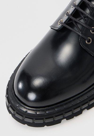 Sort, poleret lædersko med rund tå, struktureret gummisål og metaløjer til snørebånd, der har en glat og elegant finish.