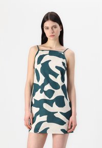 Dress camicia in tessuto beige con un motivo astratto verde. Il design include spalline sottili e una silhouette dritta, con una texture liscia.