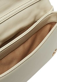 Interno della borsa a mano in pelle beige, con una fodera in tessuto marrone e due scomparti caratterizzati da una superficie morbida e dettagli di cucitura sottili.