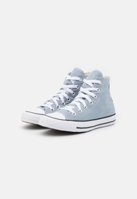 High-top sneakers in light blue canvas with white laces, black accent stripes, and a rubber toe cap. Textured surface and stitched details.