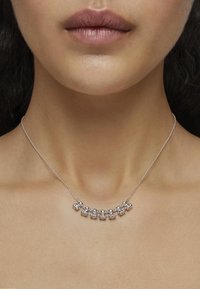 Collar de plata con cuentas circulares dispuestas en un diseño curvado, con una cadena delicada. Sin texturas ni patrones prominentes.