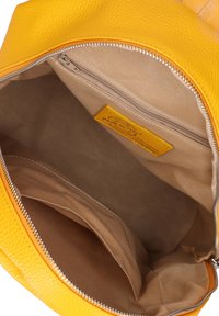 Interno di una borsa in pelle gialla texturizzata, con fodera in tessuto beige, tasca con zip e una tasca interna per l'organizzazione.