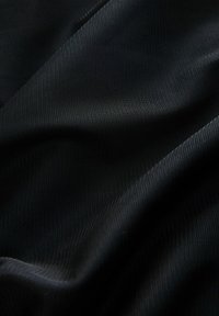 Fekete, texturált szövet finom hálószerű mintával, sima hullámokkal és diszkrét fénylésével, amely kiemeli mélységét és dimenzióját.