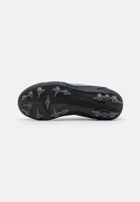 Suela de zapato atlético negro con goma negra moldeada y clavos grises, que presenta patrones texturizados para mayor agarre y un diseño aerodinámico.