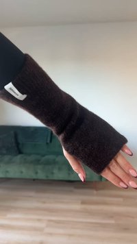 Hnědé pletené arm warmers s těsným střihem a bezprstým designem. Mají texturovaný povrch a malou značkovou etiketu na zápěstí.