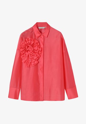 Korálová halenka s dlouhým rukávem, zapínáním na knoflíky vpředu a velkým vrstveným volánem na levé straně hrudi, s klasickým límcem a širokými manžetami.