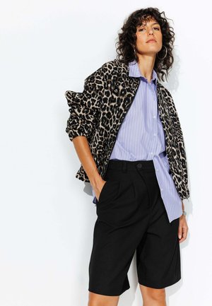 Veste bomber à imprimé léopard sur une chemise rayée bleu clair, associée à un short plissé noir. Comprend une coupe décontractée et des poches.