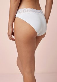 Witte katoenen slip met een decoratieve kant tailleband. De stof is glad en rekbaar, met een klassieke hoge snit.
