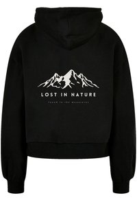 Schwarze Kapuzenjacke mit einem kurzen Design, versehen mit einer weißen Berggrafik und dem Text "VERLOREN IN DER NATUR" über "gefunden in den Bergen". Weiche Textur.