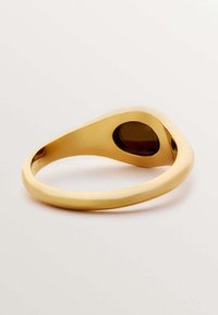 Anillo de oro con un diseño suave y curvado. Presenta un corte ovalado en un lado con una superficie brillante y un acabado pulido.