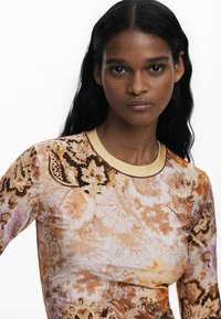 Langärmliges Oberteil mit floralem Druck in Brauntönen und Beige, mit einem runden Halsausschnitt und dezenten Perlendetails.