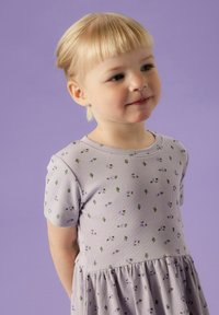 Vaaleanvioletti ribattu mekko, jossa on lyhyet hihat, liehutettu hame ja kukkakuosi vihreillä ja violetilla yksityiskohdilla. Sileä pinta.