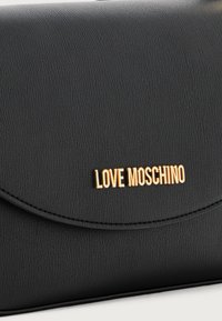 Schwarze Clutch aus strukturiertem Leder mit goldenem "LOVE MOSCHINO"-Logo auf der Vorderseite. Sie verfügt über einen runden Klappenverschluss und ein minimalistisches Design.