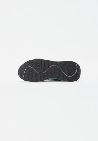 Black rubber shoe sole with textured grip patterns and a curved edge. Features a light tread and a subtle golden accent along the side.