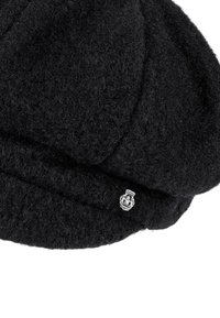 Black woolen newsboy cap with a small silver emblem featuring a tower and floral design on the side.