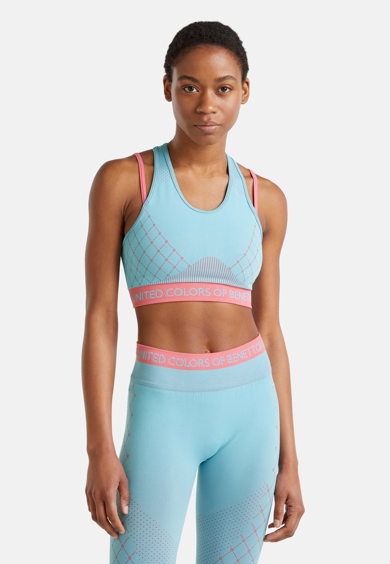 Lichtblauwe sportbh en bijpassende legging met roze accenten. Bevat geometrische patronen en branding langs de tailleband en zoom.