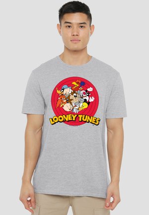 Man wearing a grey t-shirt with colorful Looney Tunes characters inside a red circle and yellow "LOONEY TUNES" text below.