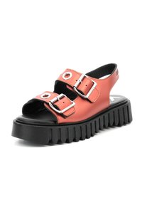 Sandalias de plataforma de color coral, hechas de material sintético suave, con dos correas con hebillas, recortes redondos y una suela gruesa de goma negra con surcos.