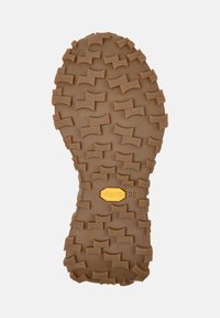 Hnědá gumová podrážka s hlubokými vzory; žluté logo "Vibram 38" viditelné uprostřed, což naznačuje odolnou obuv pro venkovní aktivity.
