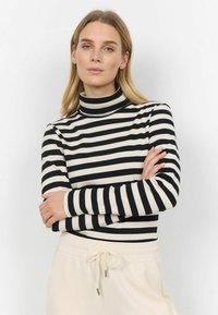 Black and cream striped turtleneck top with long sleeves, featuring a fitted design and a soft texture, paired with light beige joggers.