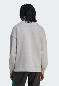 Felpa grigia con vestibilità morbida, scollo rotondo e spalle scese. Tessuto morbido, polsini a coste e piccolo dettaglio del logo sul collo.