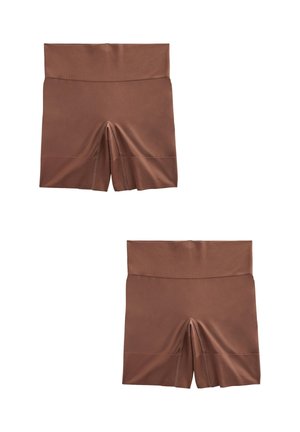 Femme portant un short de compression marron taille haute sans coutures et un soutien-gorge de sport assorti, montrant la zone médiane et le haut des cuisses.