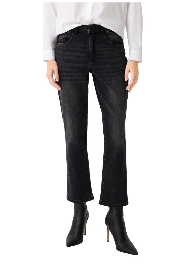 Jeans neri in denim con taglio dritto, cinque tasche e una texture leggermente sbiadita, abbinati a stivaletti neri a punta con tacco a stiletto.