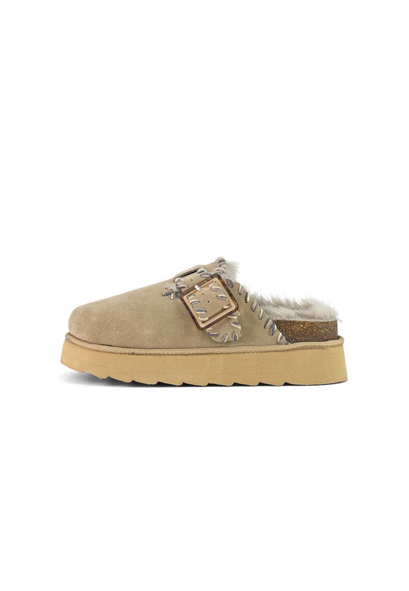 Pantofola in suede color beige con interno foderato in pelliccia, suola in gomma robusta, dettaglio con fibbia e accenti di cucitura in contrasto. Design con retro chiuso.