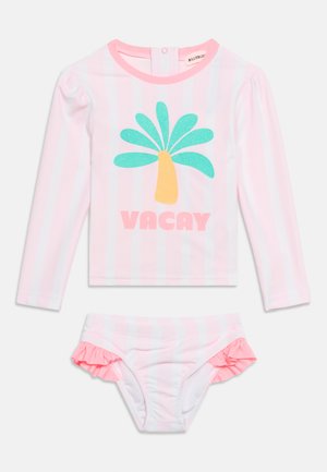 Roze-wit gestreept badpak met lange mouwen, met glinsterende palmboom en de tekst "VACAY" op het bovenstuk, en gerimpelde zijkanten aan de bikinibroekjes.