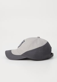 Grå og svart baseballcaps med buet skjerm, teksturert stoff og brodert logo på siden. Justerbar stropp bak.
