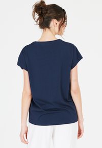 Mörkblå, kortärmad t-shirt med en avslappnad passform. Mjuk textur och enkel design, med rundad halsringning och något sänkta axlar.