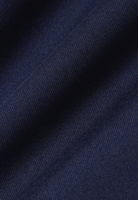 Tissu bleu foncé tissé avec une texture fine visible en gros plan, mettant en valeur le tissage diagonal et les plis subtils.