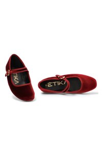 Bailarinas de terciopelo rojo con punta redondeada, tira en el tobillo y hebilla en tono dorado. Textura suave y plantilla acolchada para mayor comodidad.