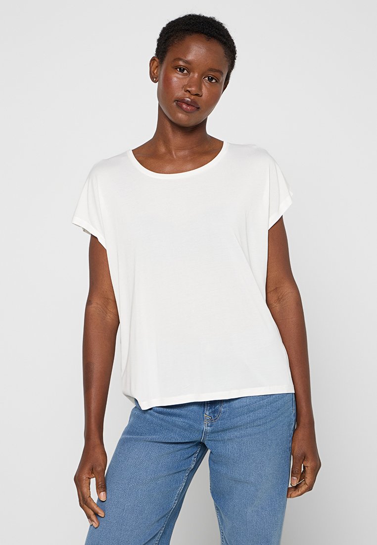 Witte t-shirt met korte mouwen van zachte stof; heeft een losse pasvorm en een ronde halslijn, gecombineerd met blauwe denim jeans.