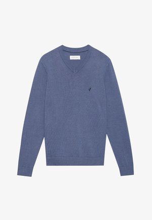 Sötétkék V-nyakú pulóver, texturált kötött anyagból készült. Hosszú ujjakkal rendelkezik, és egy kis logó található a mellkason. Az ujjak és az alj díszített.