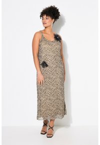 Robe maxi en imprimé léopard avec bretelles spaghetti, présentant un accent floral noir sur l'épaule et une poche latérale. Tissu lisse et léger.