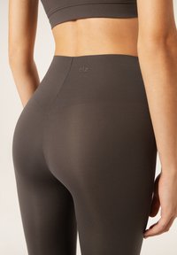 Hoge taille, donkergrijze leggings gemaakt van een gladde, rekbare stof. Heeft een subtiel logo en een naadloos ontwerp voor comfort.