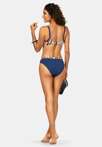 Niebieski bikini z wzorzystą górą; jednolite granatowe dno. Regulowane ramiączka, niski krój i minimalna osłona. Gładka faktura z elastycznym pasem.