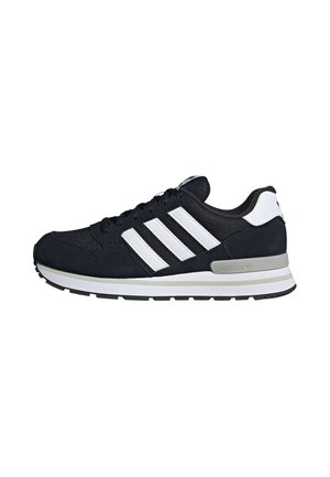 Musta-valkoinen Adidas-tennari, jossa kolme valkoista raitaa, edessä nyöritys ja harmaa pehmustettu pohja valkoisella taustalla.