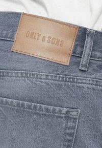 Τζιν τζιν σε ανοιχτό γκρι με δερμάτινο ταμπελάκι με την ένδειξη "ONLY & SONS", με κανονική τσέπη και λεπτομέρειες ενισχυμένης ραφής.