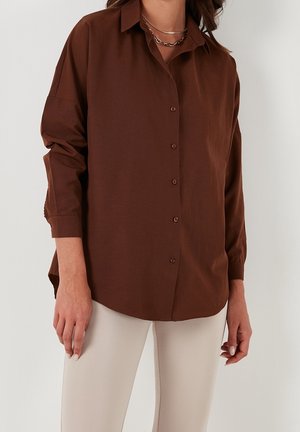 Chemise brun à col, à manches longues et à coupe décontractée. Fabriquée en tissu doux, elle présente un ourlet droit et peu de détails.