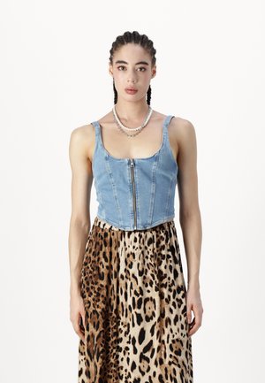 Top in denim tagliato, con zip frontale, abbinato a una gonna leopardata marrone e nera. Presenta spalline larghe e un design aderente.