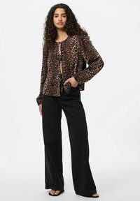 Camicia a righe leopardate con bottoni, con un nodo davanti, maniche lunghe, vestibilità rilassata, realizzata in tessuto leggero. Abbinata a pantaloni neri a zampa.