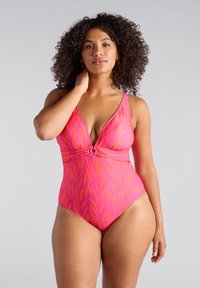 Rosa baddräkt i ett stycke med djup V-ringning, tvistad frontdetalj, lövdesign och justerbara band. Slät tyg med en figurnära silhuett.