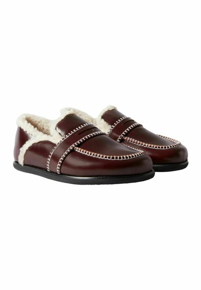 Pantofole in pelle bordeaux con foderatura in pelliccia sintetica, caratterizzate da cuciture decorative bianche e una suola piatta nera. Design slip-on senza chiusure.
