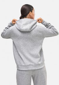 Sudadera gris con cordón y una capucha espaciosa, hecha de una tela suave. Presenta puños y dobladillo acanalados para un ajuste ceñido.