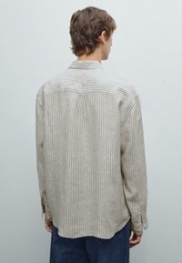 Gestreifte, leichte, langärmelige Bluse in Beige und Off-White. Besitzt einen Rückenpasse und seitliche Schlitzungen. Lässige Passform mit Knopfmanschetten.