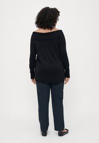 Pulover negru, fără umeri, cu guler corset, asortat cu pantaloni bleumarin. Ambele articole au o textură netedă și un croi lejer.