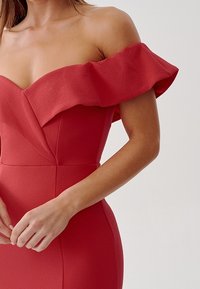 Rød off-the-shoulder kjole med en rynket halsudskæring, struktureret stof, tætsiddende bodice og detaljeret taljesøm for en skræddersyet silhuet.