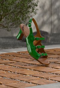 Sandale en cuir verni vert avec trois brides réglables et un détail boucle ; dotée d'une semelle intérieure rembourrée couleur marron clair et d'un petit talon bloc.